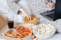 Emotional Eating image of woman surrounded by unhealthy food